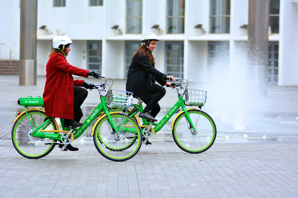 Man and woman in helmets cycling on green bikes