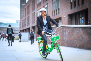 Man with helmet on lime green bike in city centre