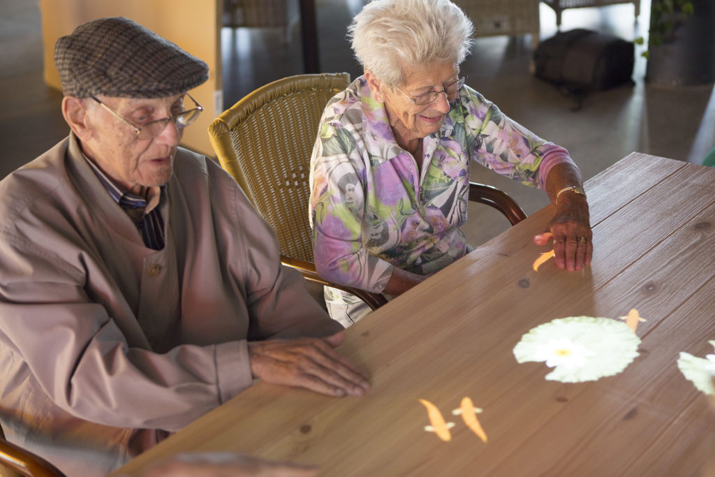 Two older people doing jigsaw puzzle at table
