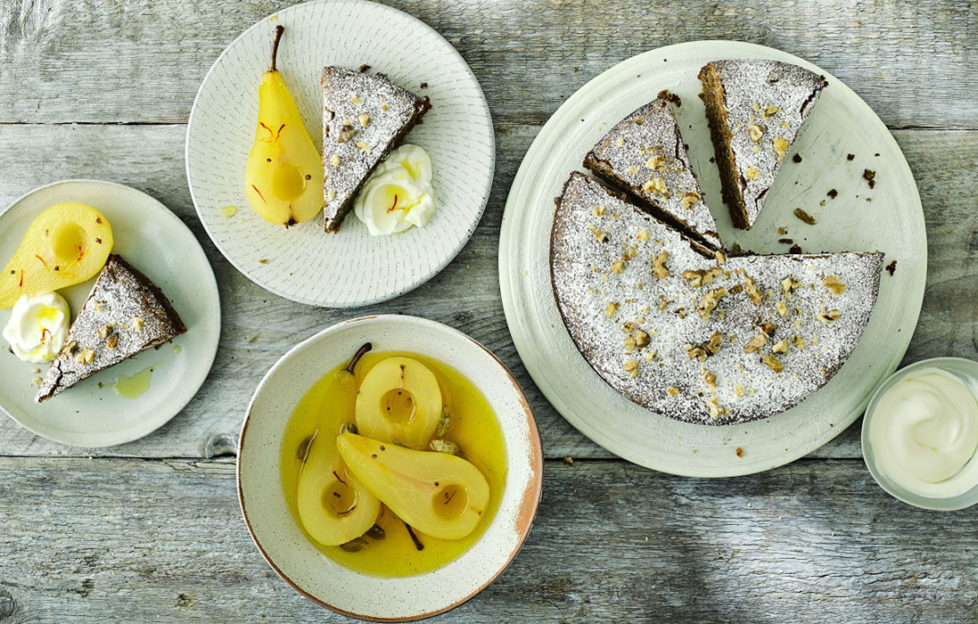 Sugar-dusted cake, 3 slices cut, dish of golden poached pears and 2 small plates with cake slice and a pear