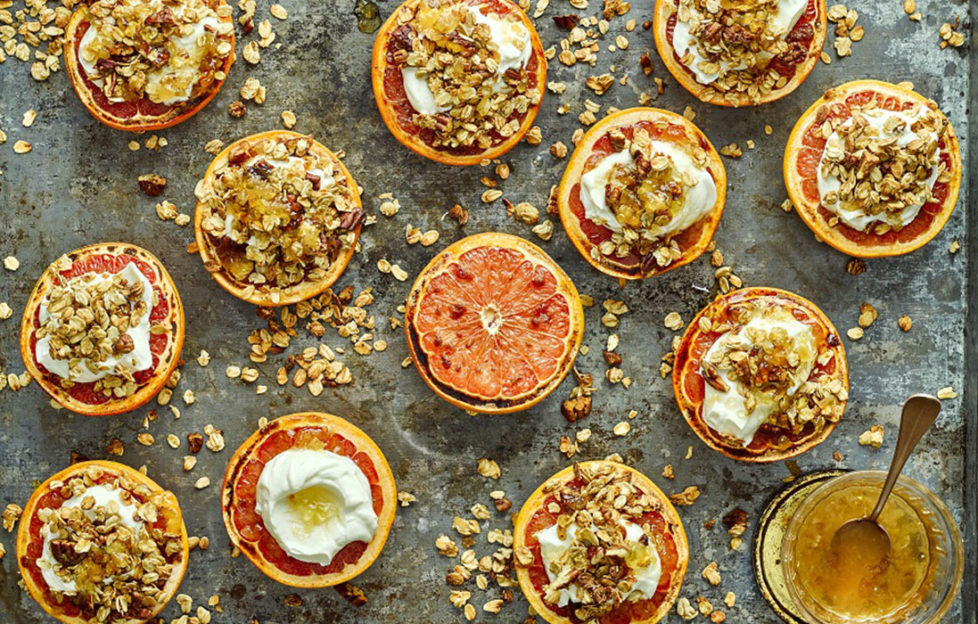 13 grapefruit halves, most topped with golden granola and yogurt