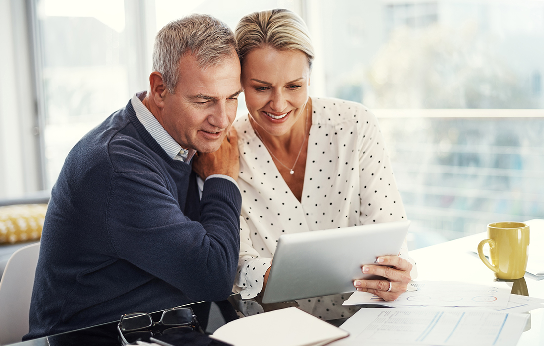 Shot of a mature couple using a digital tablet while going through paperwork at home