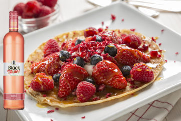 Pancake topped with berries with Black Tower Rose wine at the side of the image