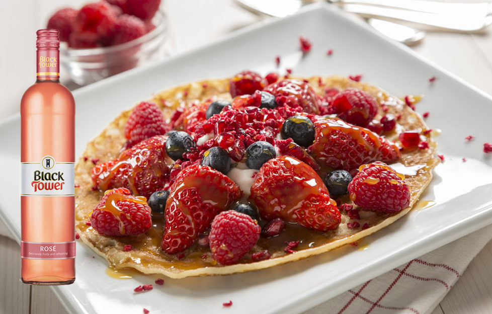 Pancake topped with berries with Black Tower Rose wine at the side of the image