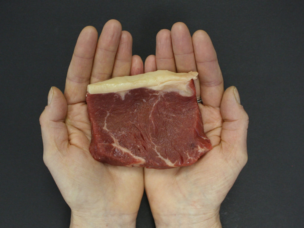 Hands holding red steak