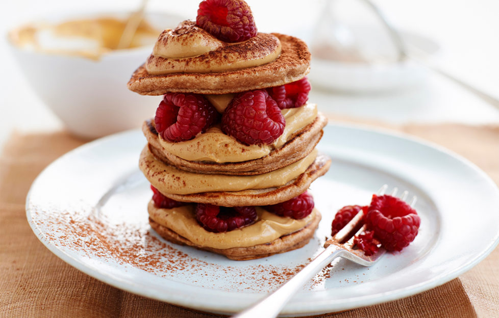 Stack of small pancakes layered with coffee coloured mascarpone and fresh raspberries