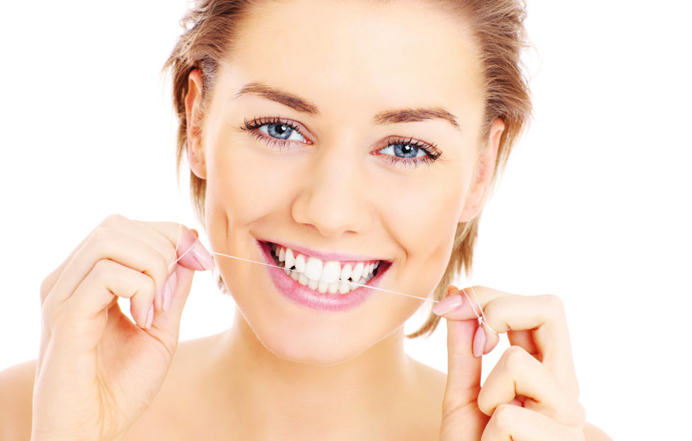 A picture of beautiful womanusing a floss for her teeth over white background