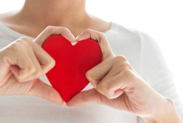 Young woman's hands holding a red heart. Love and health care concept.