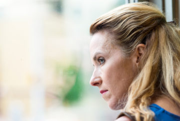 Pensive Mature blonde woman looking out of window