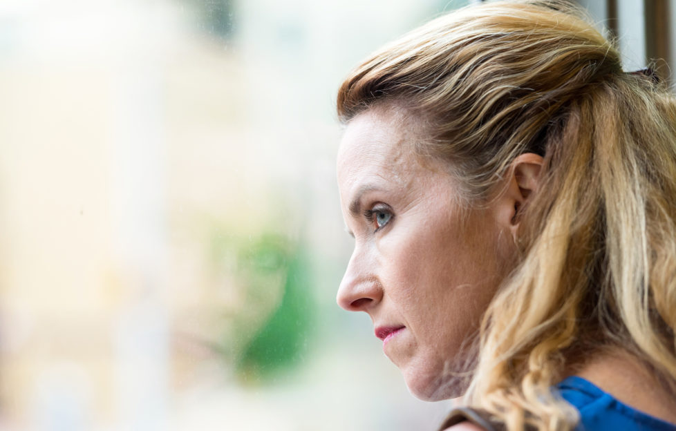 Pensive Mature blonde woman looking out of window