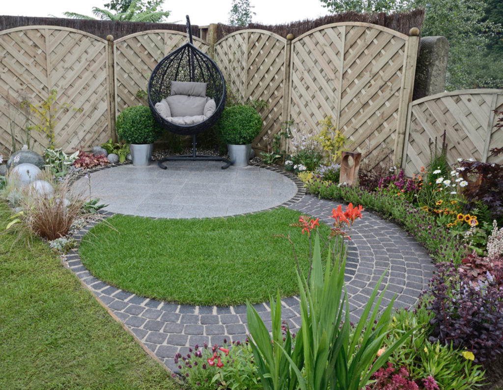 Enjoy your garden. Small garden with hanging chair and grey paved slabs