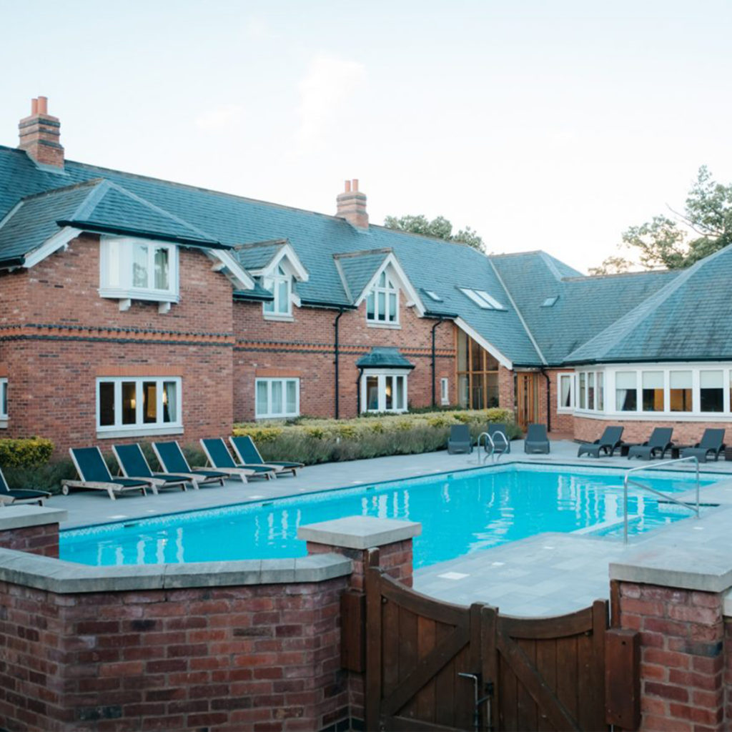 Red brick buildings and conservatory overlooking heated outdoor pool at Ardencote spa