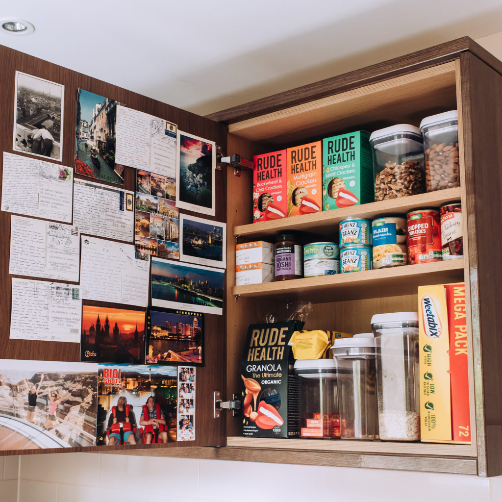 Kitchen cupboard neatly arranged with cereal packets and cans