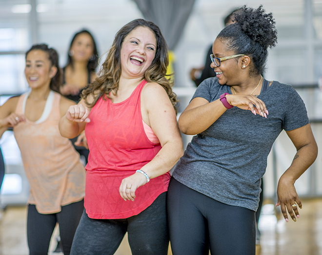 A multi-ethnic group of adult women are dancing in a fitness studio. They are wearing athletic clothes. Two women are laughing while dancing together.. Pic: istockphoto