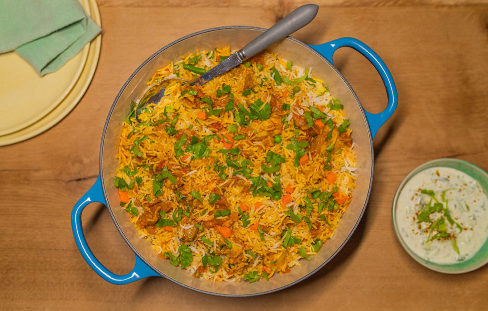 Blue casserole dish of chicken biryani with chopped coriander