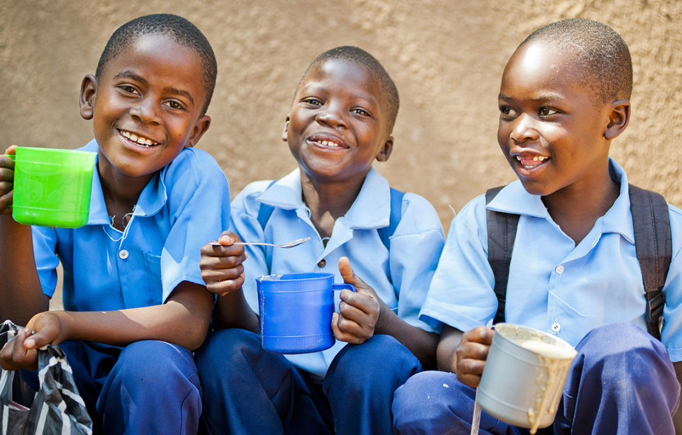 Three schoolboys in Zambia enjoying food provided by Mary's Meals Pic: Chris Watt