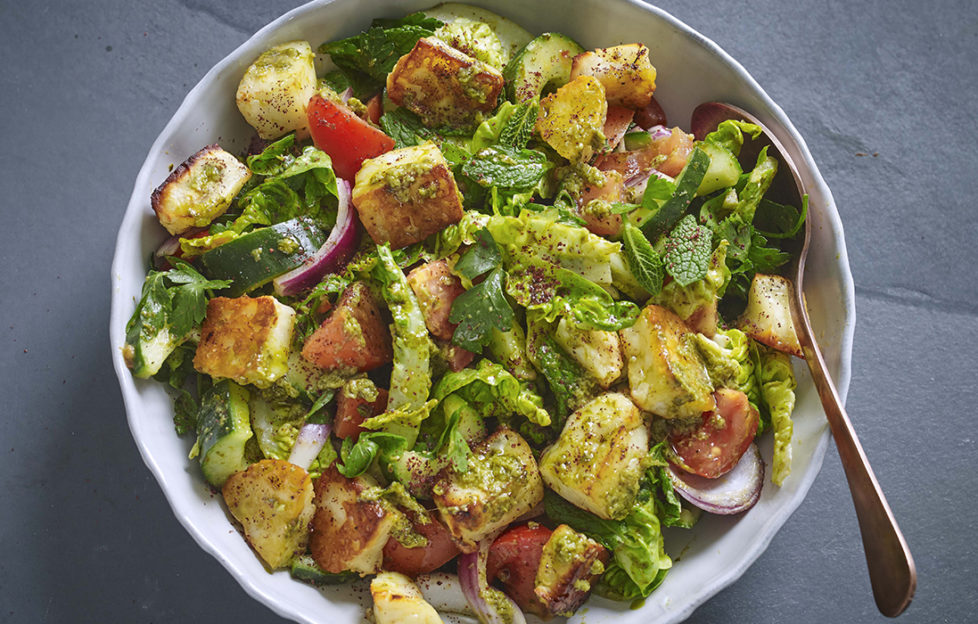 Bowl of halloumi salad with cubes of toasted cheese, cucumber, tomato, onion and tiny lettuce leaves