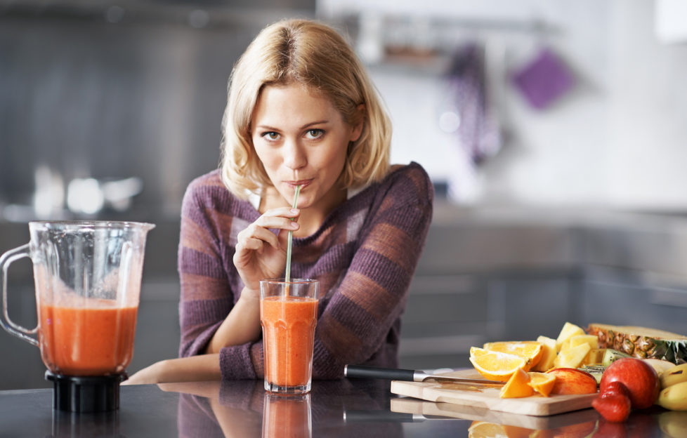 A young woman happily sipping on her homemade smoothie