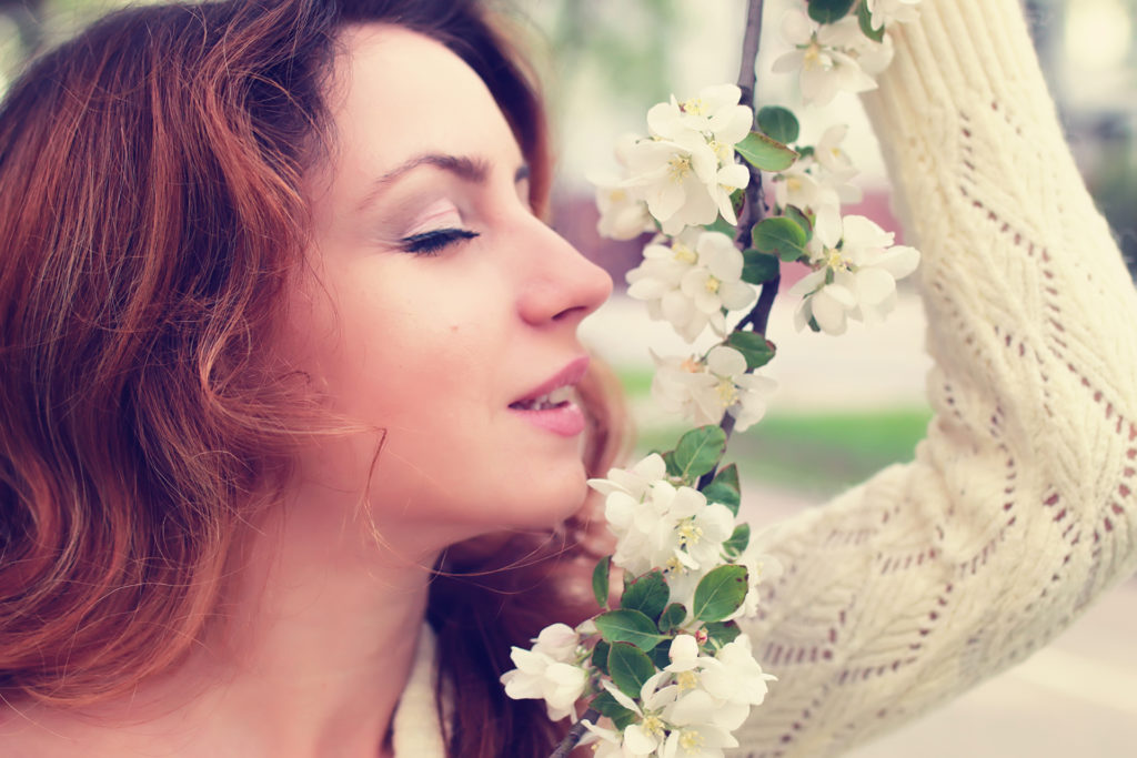 Woman smelling white flower on tree