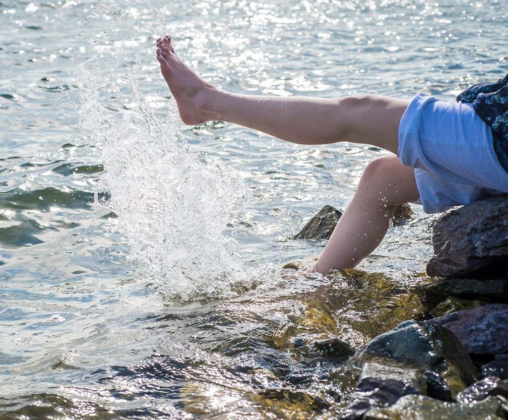 A lady splashing feet in a lake