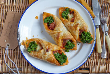 Three small puff pastry rolls, with bright green broccoli, Parma ham and melted cheese showing at each end