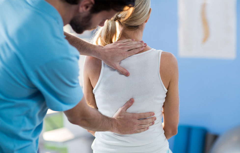 Male therapist treating woman's back, both standing