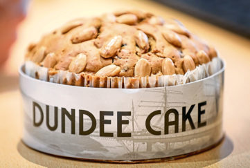 Freshly baked Dundee cake, golden brown topped with almonds, in a paper case