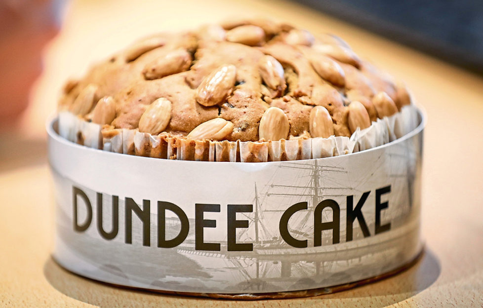 Freshly baked Dundee cake, golden brown topped with almonds, in a paper case