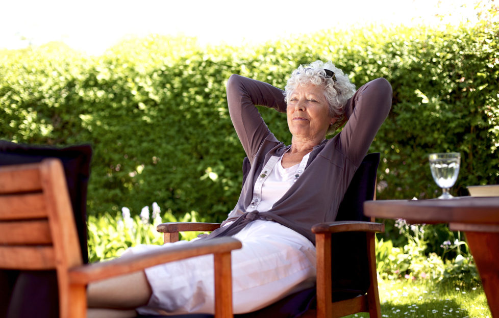 Senior woman sitting on a chair and taking a nap in backyard. Elder woman sleeping in backyard garden