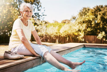 Lady dipping toes in pool looking happy Pic: Istockphoto