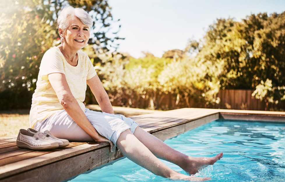 Lady dipping toes in pool looking happy Pic: Istockphoto