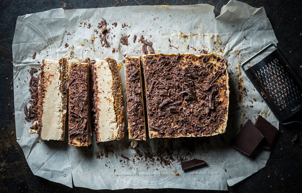 Block of vegan freezer tiramisu dessert, sprinkled with chocolate, four slices cut