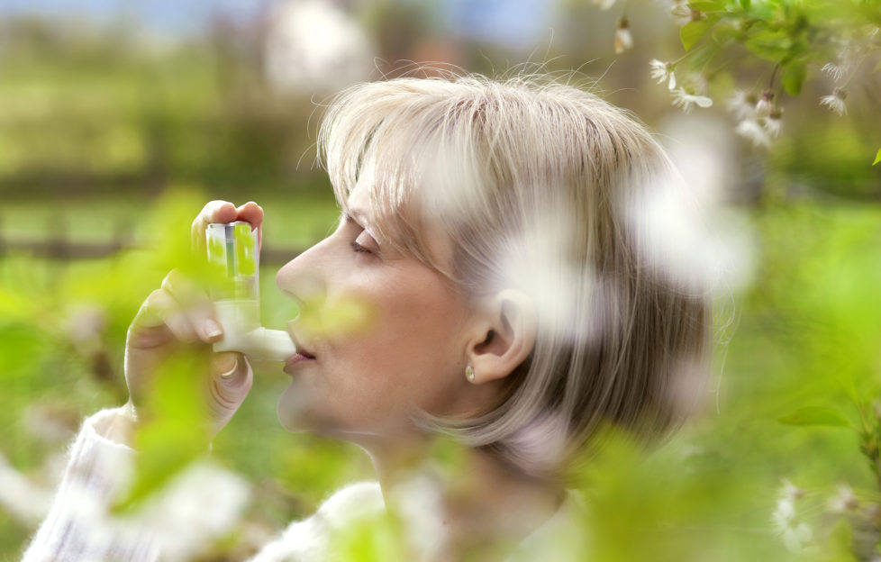 woman in the blossoming garden, using inhaler for asthma