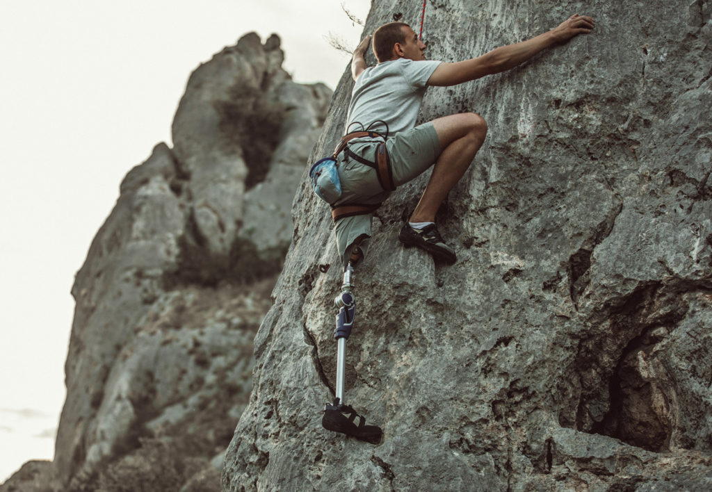 Man with space tech prosthetic leg free-climbing a rock face