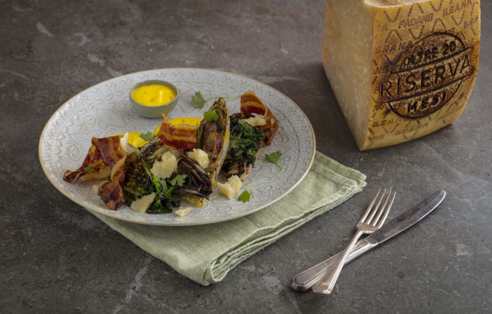 Bowl of salad with cheese, pancetta and big block of Grana Padano on the side