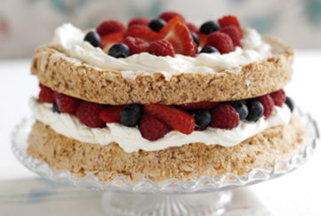 Macaroon cake filled and topped with cream and fresh berries