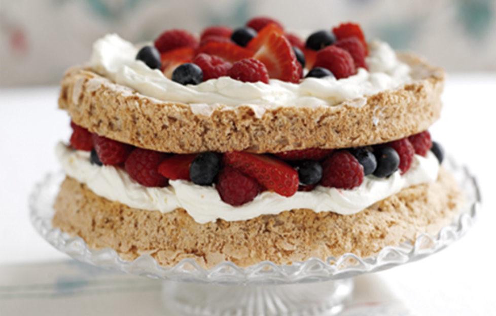 Macaroon cake filled and topped with cream and fresh berries