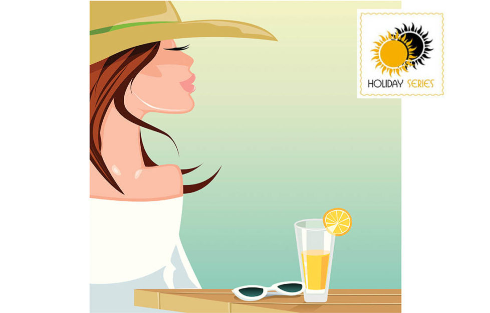 Woman in sunhat, glass of orange juice and sunglesses on cafe table in front of her, looking dreamily into distance