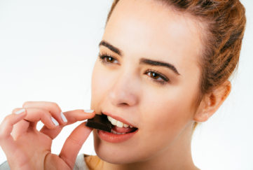 Woman eating square of dark chocolate