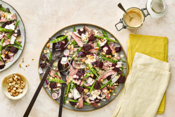 Large plate of colourful mixed salad, beetroot, sugar snaps and slices of steak, satay dressing in a dish at the side