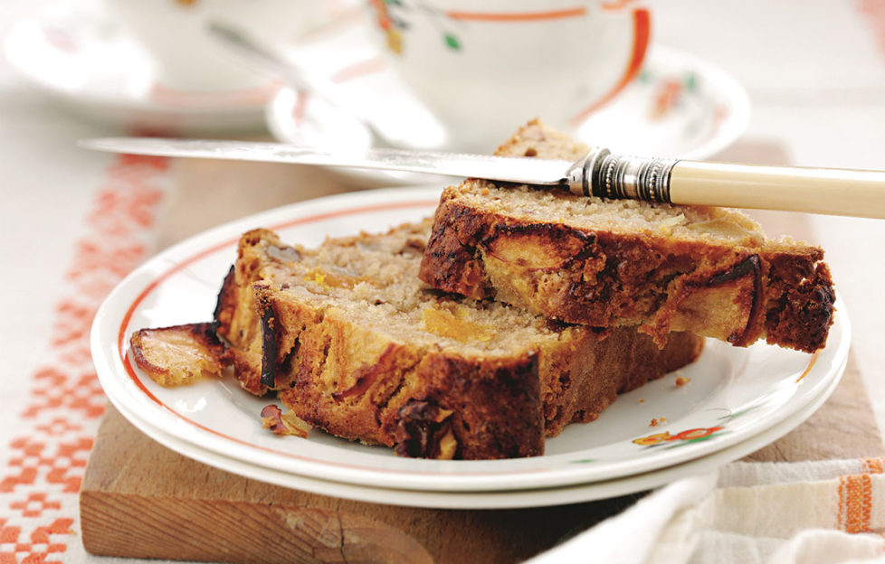 2 thick cut slices of apricot, apple and walnut loaf on a china plate, teacup behind