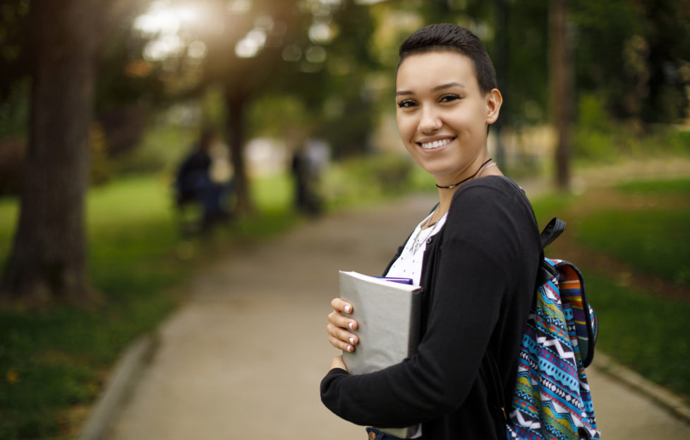Happy female college student with books on university campus