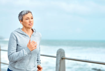 Shot of a mature woman listening to music while exercising outdoors