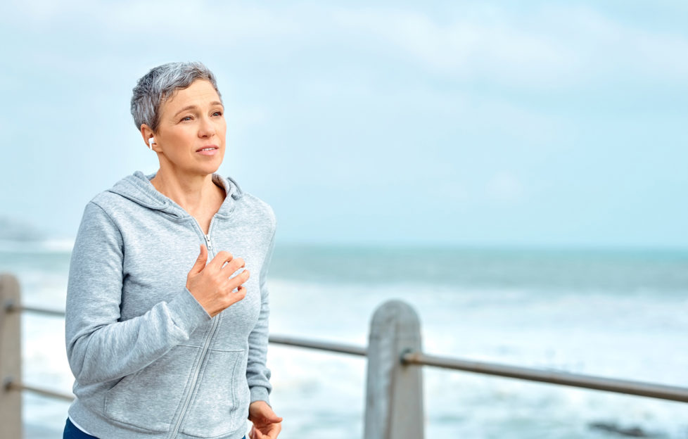 Shot of a mature woman listening to music while exercising outdoors
