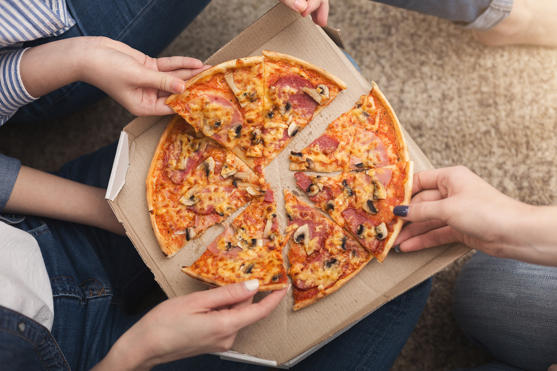 Women's hands reaching for pizza