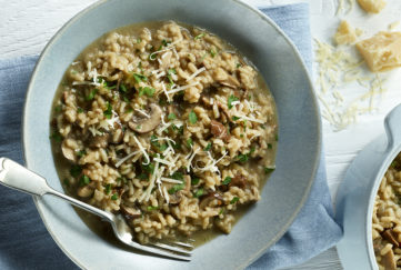 Bowl of rich brown mushroom risotto garnished with grated cheese and chopped parsley