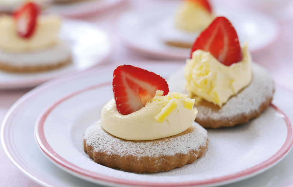 Small plate with two round shortcake biscuits, each decorated with whipped cream and half a strawberry