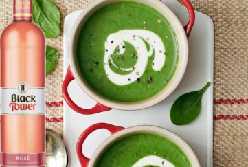 wine with soup - two bowls of rich green soup with a swirl of cream, and a bottle of rose wine