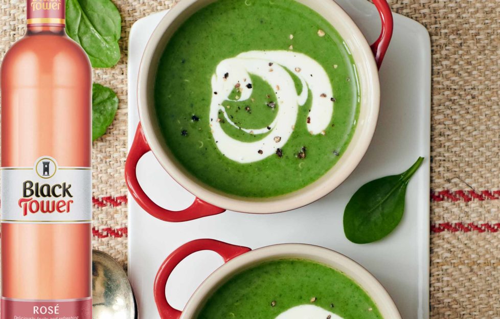 wine with soup - two bowls of rich green soup with a swirl of cream, and a bottle of rose wine