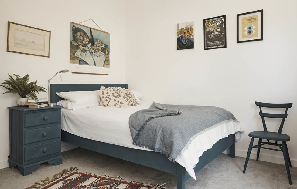 BHF makeover. Double bedroom with neutral walls and carpet, bed chair and chest painted rich dark green, patterned rug, framed prints on walls